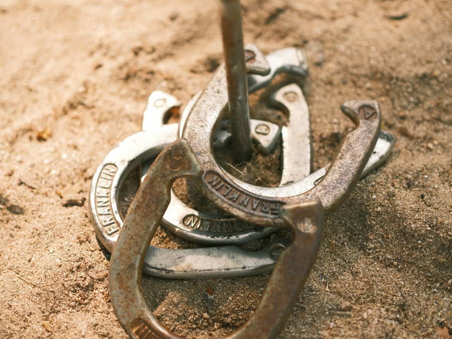 Horseshoes resting in the sand of a pitching box