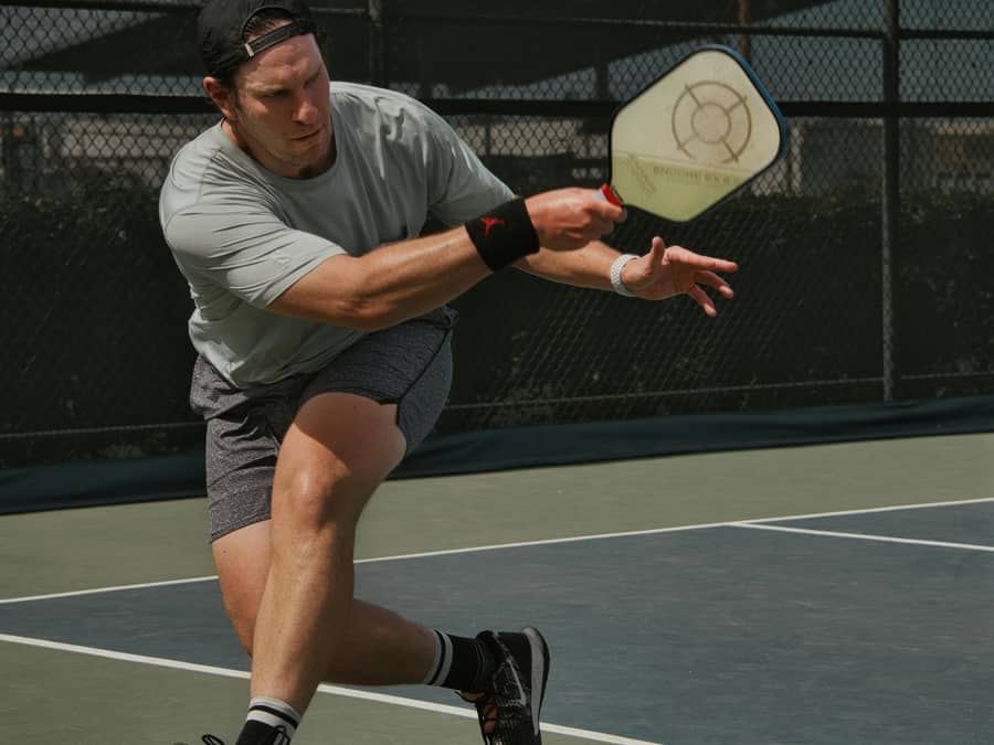 A player stretching for a return during a pickleball match